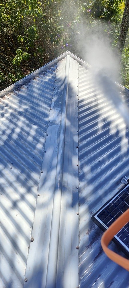 Soft washing a Colorbond metal roof in progress, Brisbane — low-pressure spray removing mould and algae