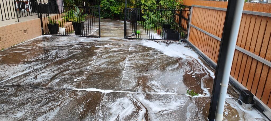 Soft washing treatment applied to a Brisbane courtyard, foam solution breaking down dirt and grime before rinsing