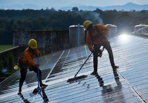 Two professional roof cleaners using soft mops to clean a residential roof in Brisbane