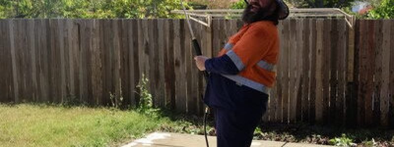 Fresh Again technician in North Lakes holding pressure washing equipment and smiling at the camera.