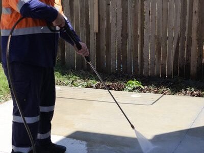 Fresh Again technician pressure washing the concrete driveway of a Redcliffe home, Brisbane Northside.