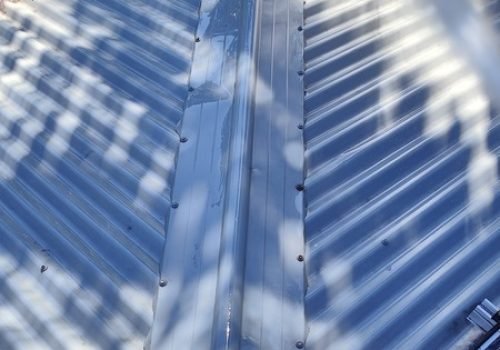 Soft washing a Colorbond metal roof in progress, Brisbane — low-pressure spray removing mould and algae